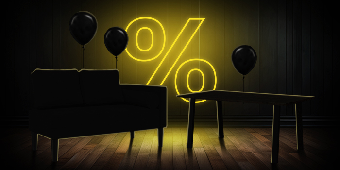 Melns dīvāns un koka galds ar melniem baloniem spoži dzeltenas procentu zīmes priekšā uz tumšas koka grīdas.